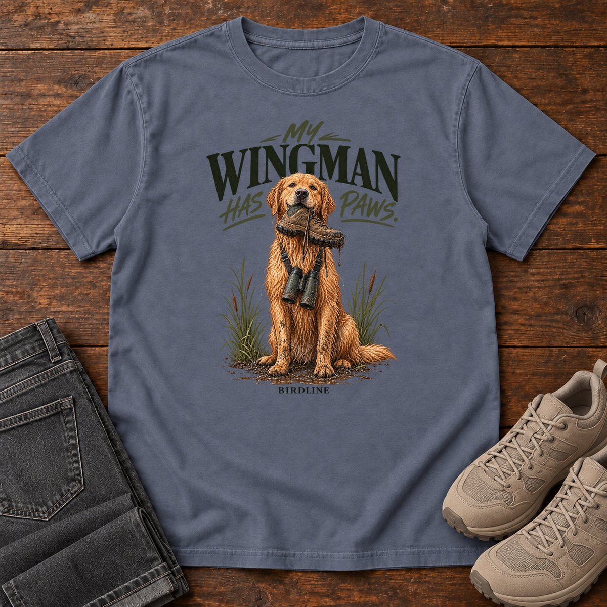 Denim My Wingman Has Paws Retriever T-Shirt with a seated golden dog wearing binoculars beneath the slogan, front flat lay on wood.
