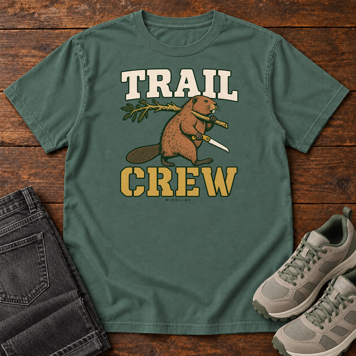 Blue Spruce Trail Crew Foreman T-Shirt with a beaver carrying a leafy branch and saw beneath Trail Crew lettering; front flat lay on wood.