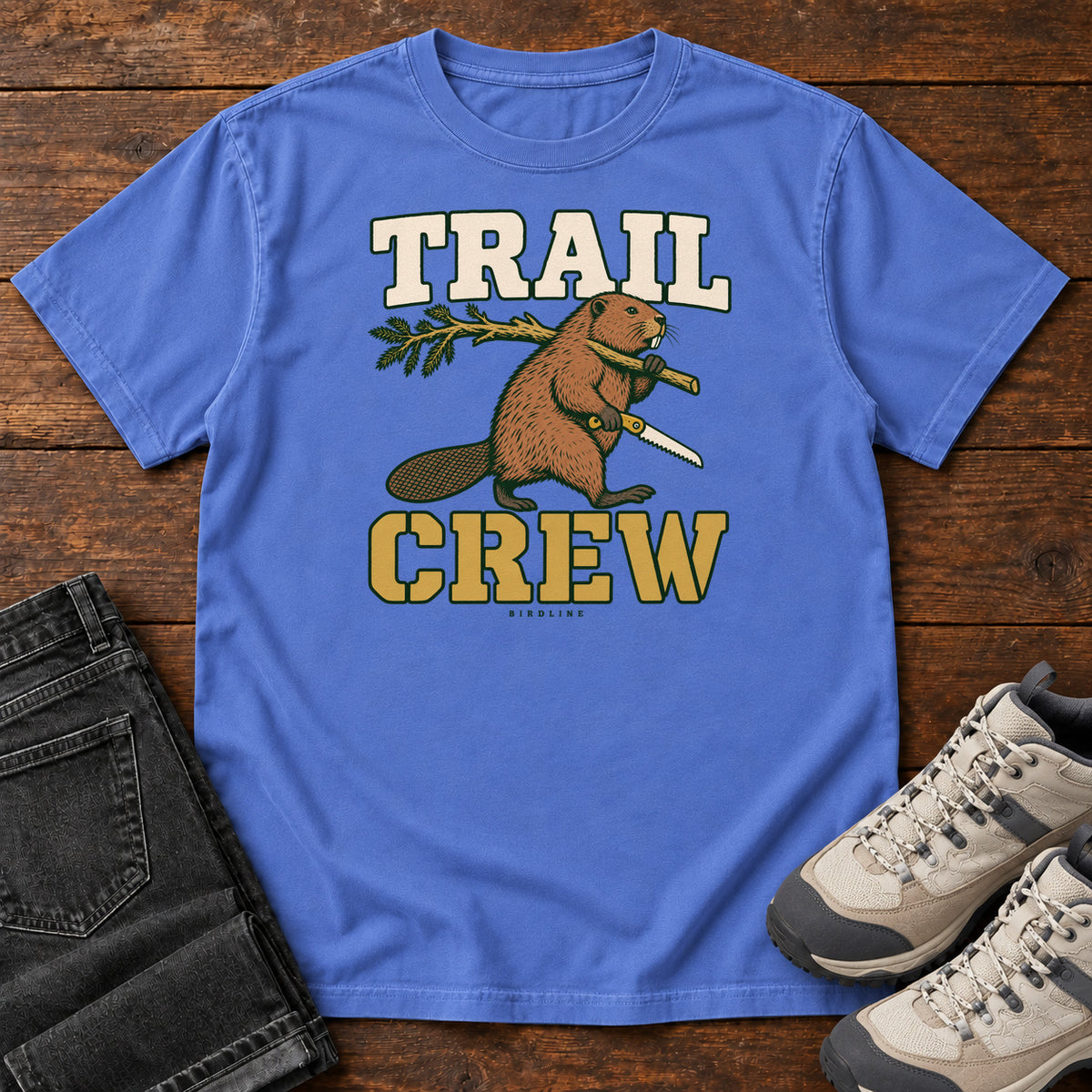 Mystic Blue Trail Crew Foreman T-Shirt with a beaver carrying a leafy branch and saw beneath Trail Crew lettering; front flat lay on wood.
