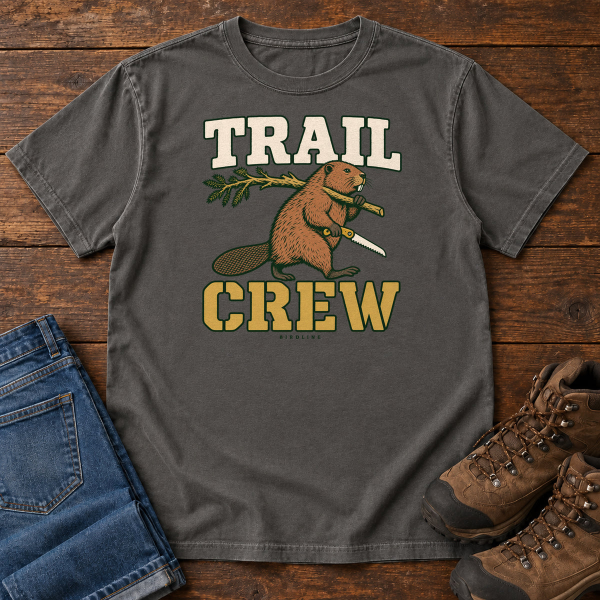Pepper Trail Crew Foreman T-Shirt with a beaver carrying a leafy branch and saw beneath Trail Crew lettering; front flat lay on wood.