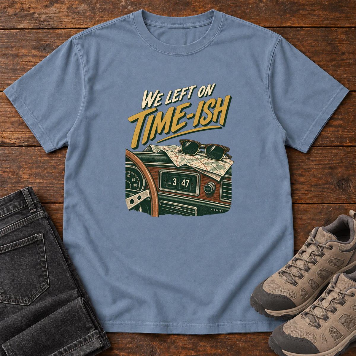 Blue Jean We Left on Time-Ish T-Shirt with a retro dashboard, folded map and sunglasses; front flat lay on wood.
