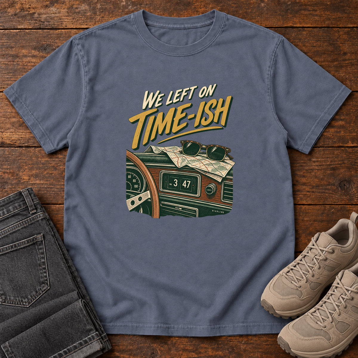 Denim We Left on Time-Ish T-Shirt with a retro dashboard, folded map and sunglasses; front flat lay on wood.