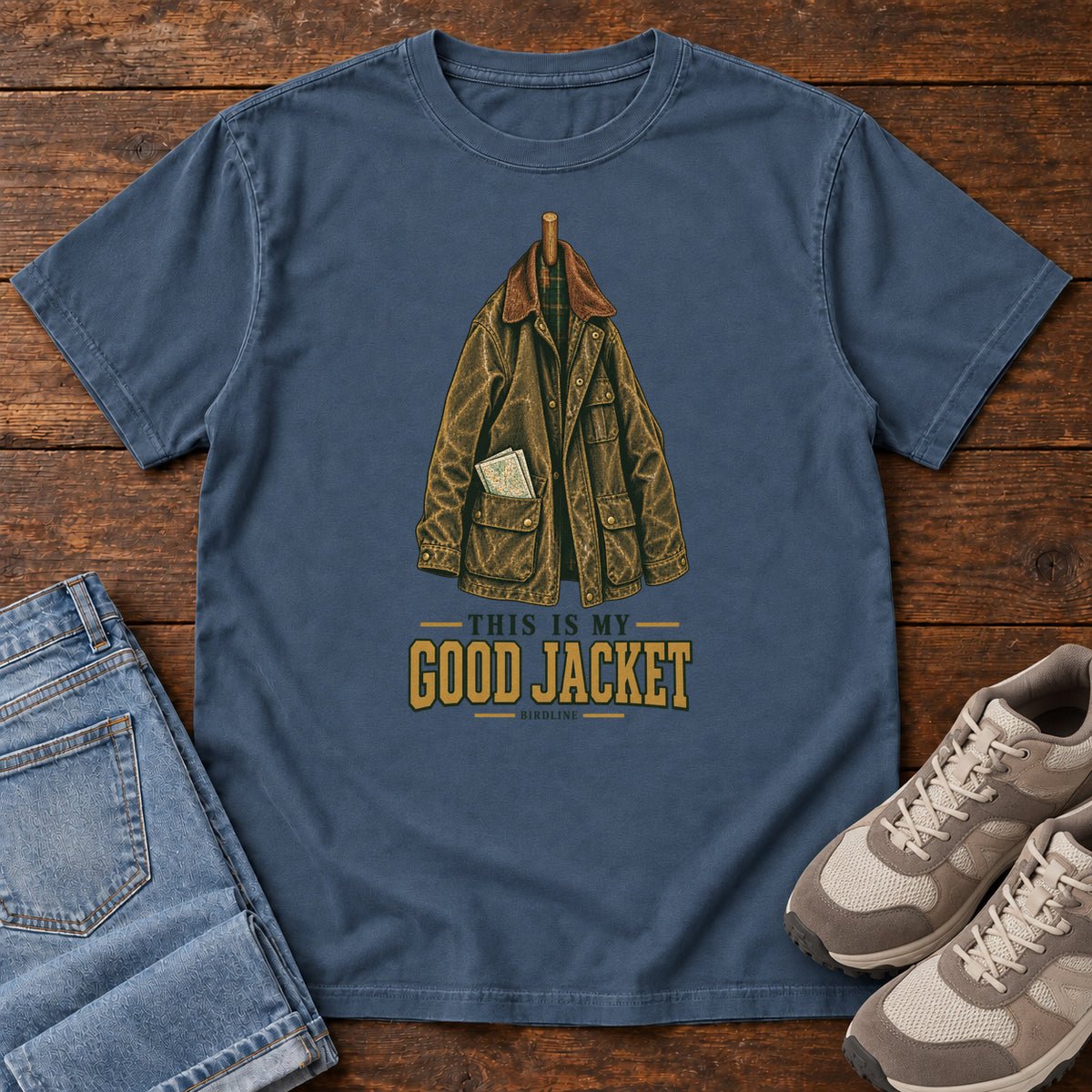 Midnight This Is My Good Jacket T-Shirt with a hanging outdoor jacket and This Is My Good Jacket lettering; front flat lay on wood.