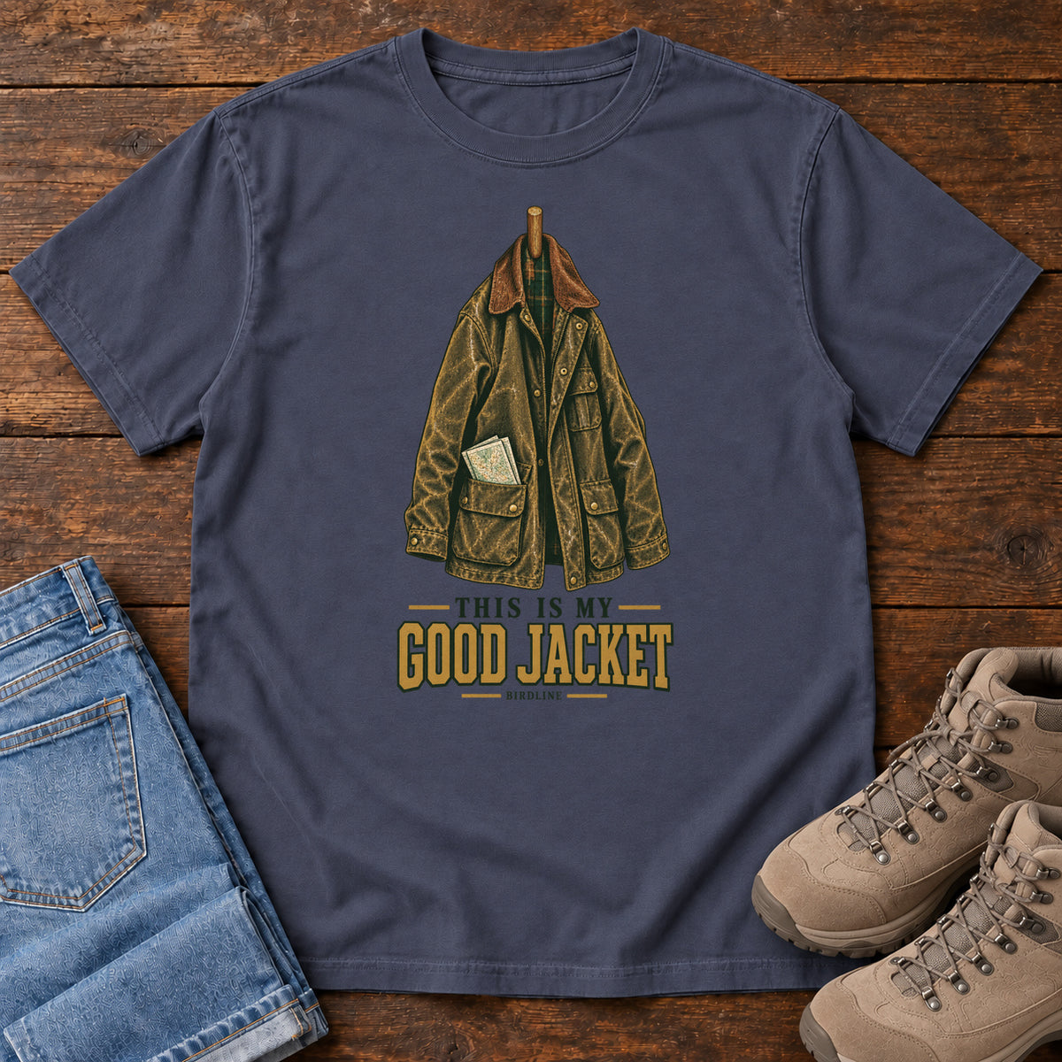 Navy This Is My Good Jacket T-Shirt with a hanging outdoor jacket and This Is My Good Jacket lettering; front flat lay on wood.