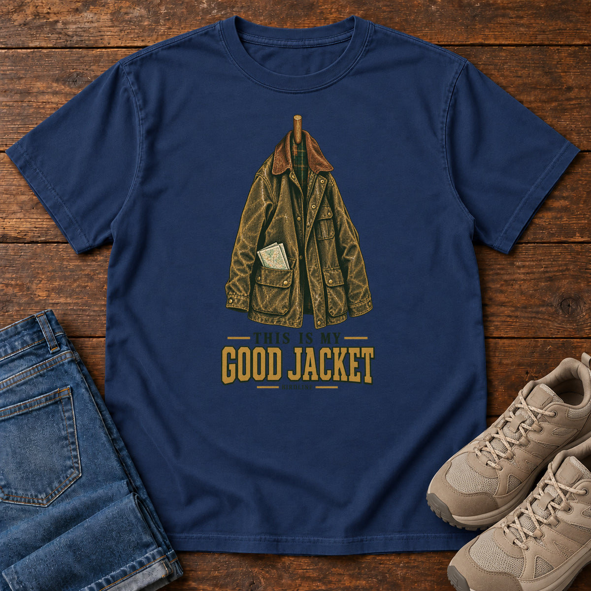 True Navy This Is My Good Jacket T-Shirt with a hanging outdoor jacket and This Is My Good Jacket lettering; front flat lay on wood.