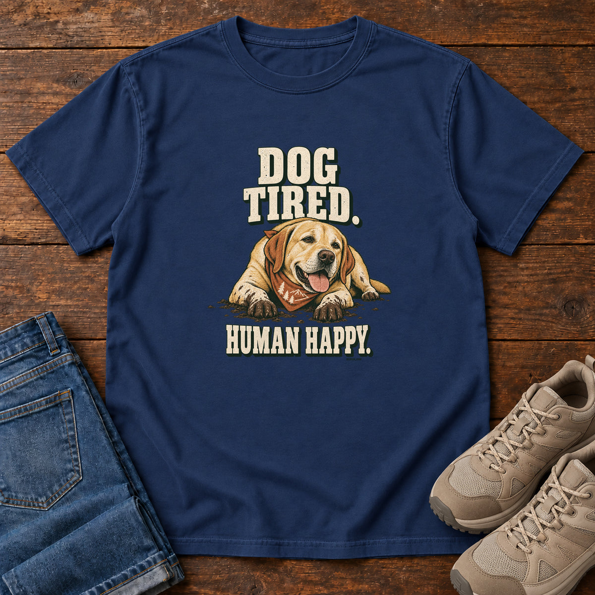 Dog Tired Human Happy T-Shirt in True Navy, front laid flat on wood, featuring a resting golden-brown dog wearing an orange bandana between cream slogan lettering.