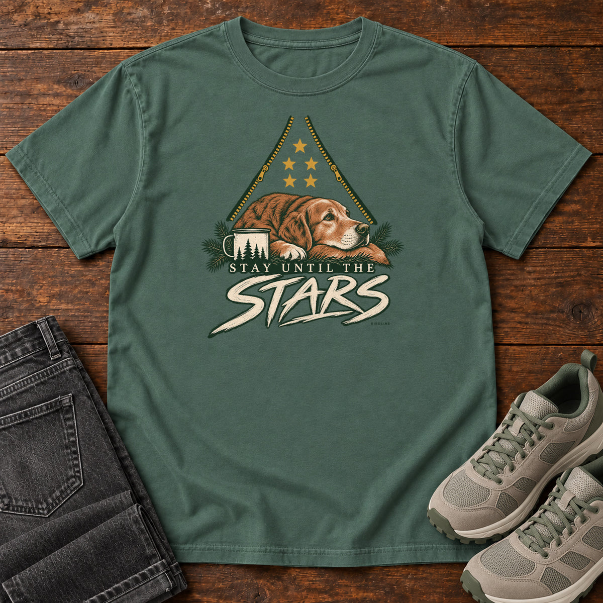 Blue Spruce Stay Until the Stars T-Shirt with a resting brown dog beside a camp mug beneath gold stars and cream lettering, front flat lay on wood.