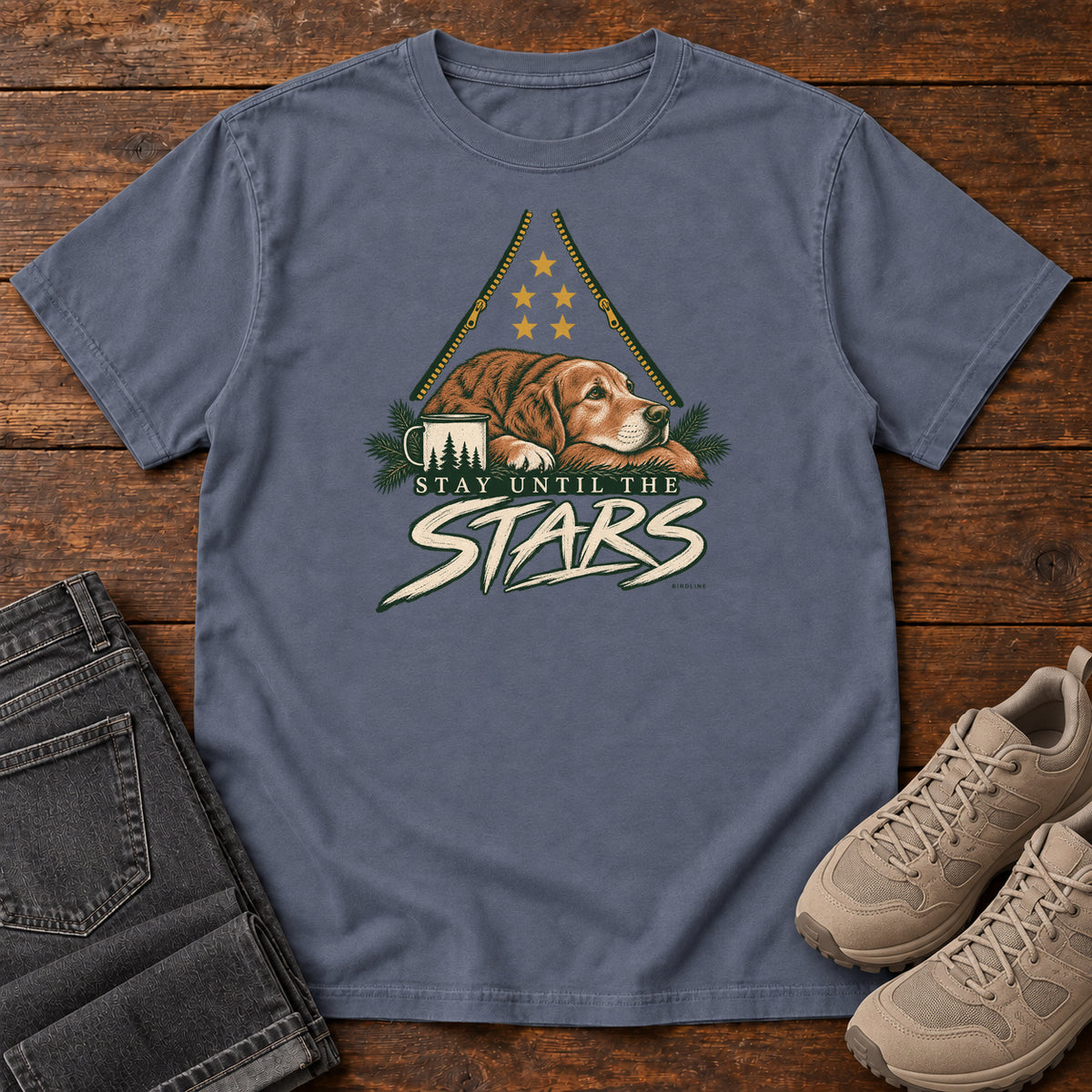 Denim Stay Until the Stars T-Shirt with a resting brown dog beside a camp mug beneath gold stars and cream lettering, front flat lay on wood.