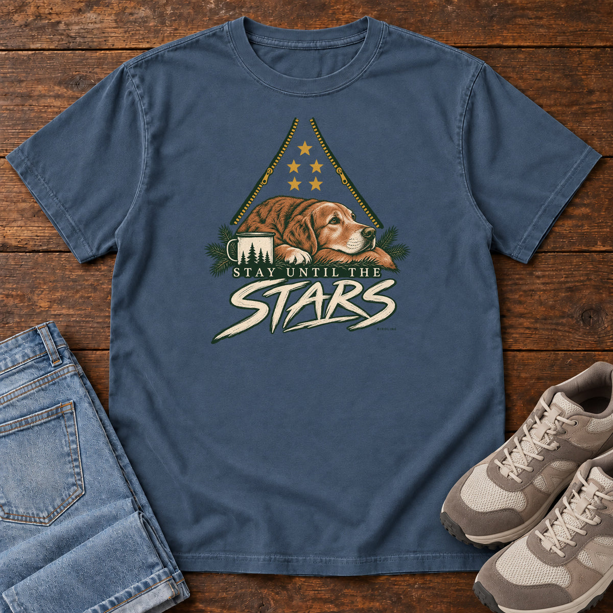Midnight Stay Until the Stars T-Shirt with a resting brown dog beside a camp mug beneath gold stars and cream lettering, front flat lay on wood.
