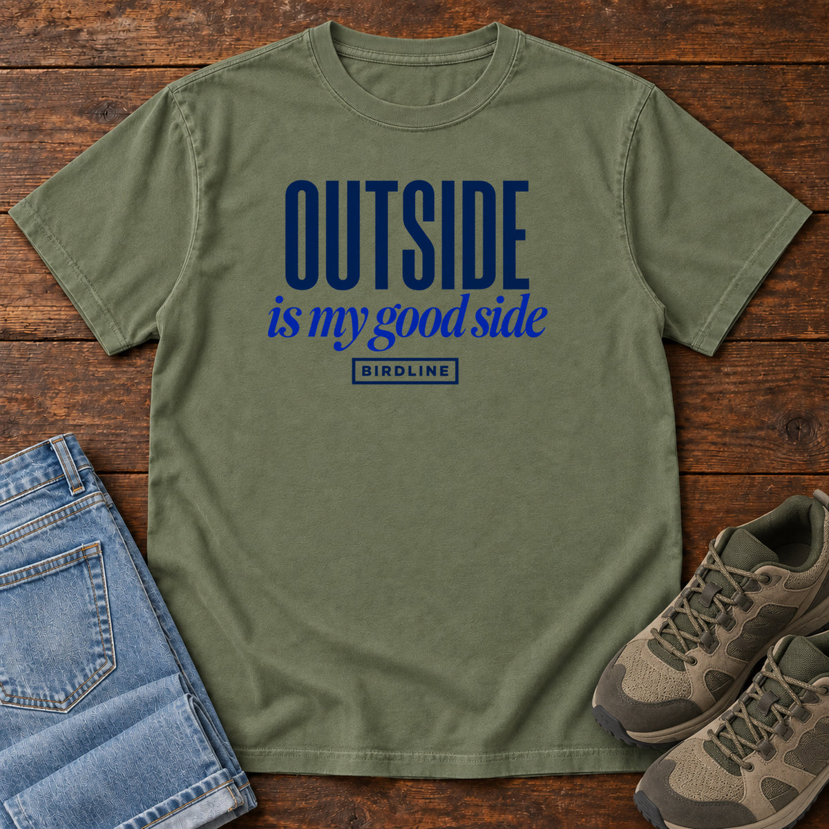 Moss Outside Is My Good Side T-Shirt with dark blue block-and-script lettering, front flat lay on wood.