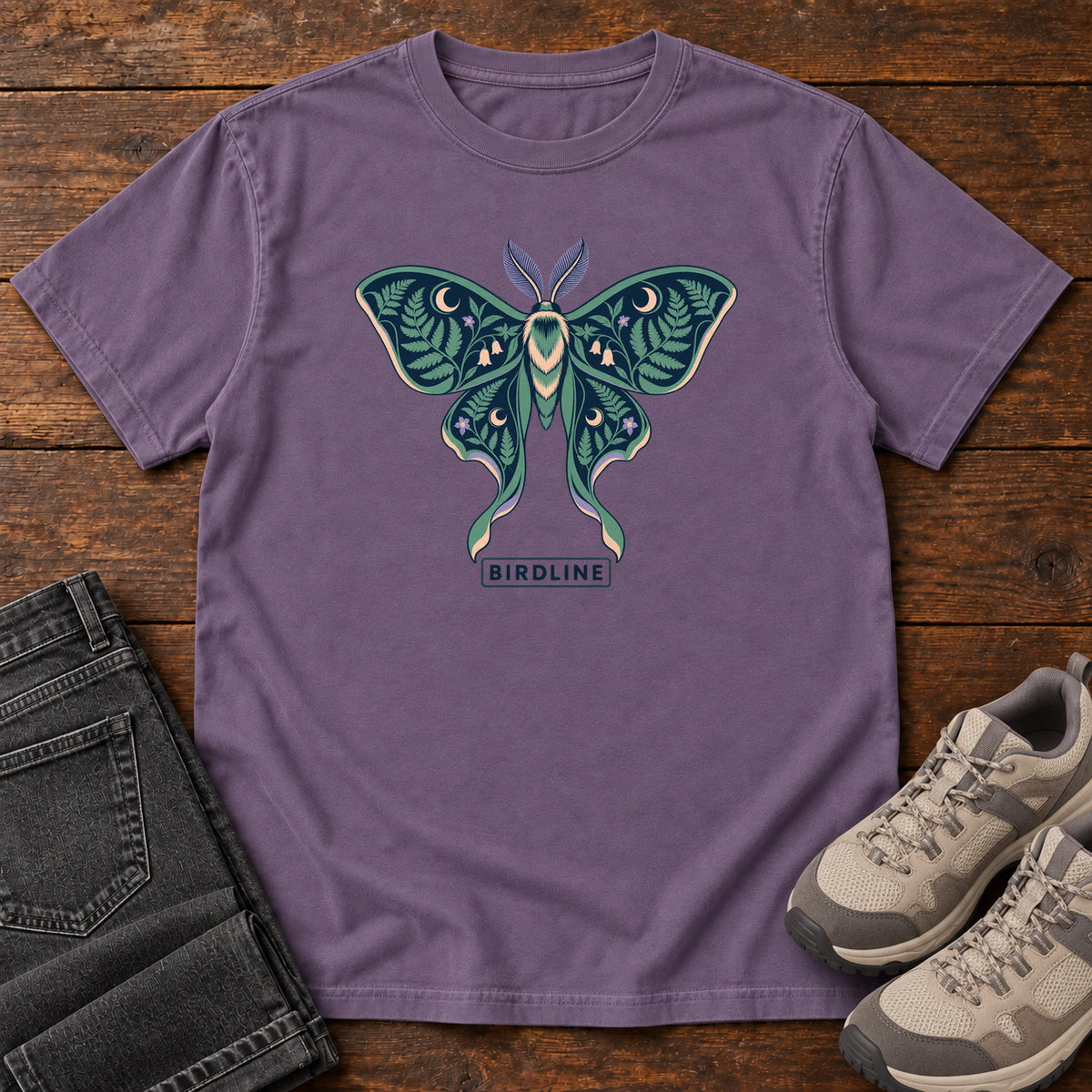 Botanical Moth T-Shirt in Grape, front laid flat on wood, featuring a teal moth with patterned wings, leaves and crescent moons.