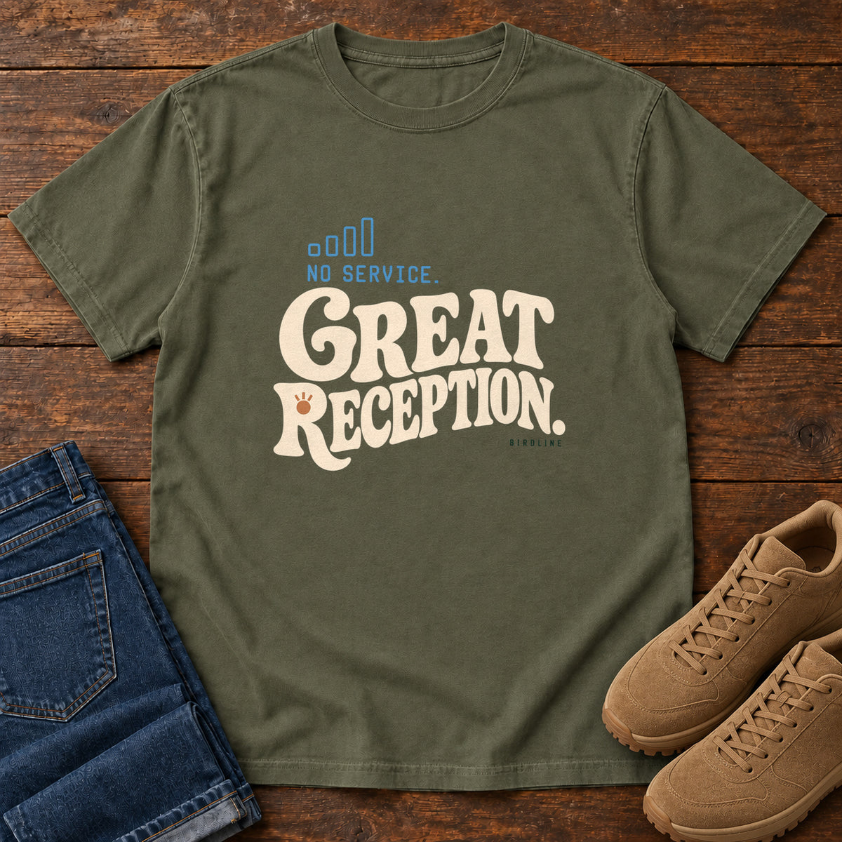 Sage No Service. Great Reception. T-Shirt with cream retro lettering and blue outlined phone-signal bars; front flat lay on wood.