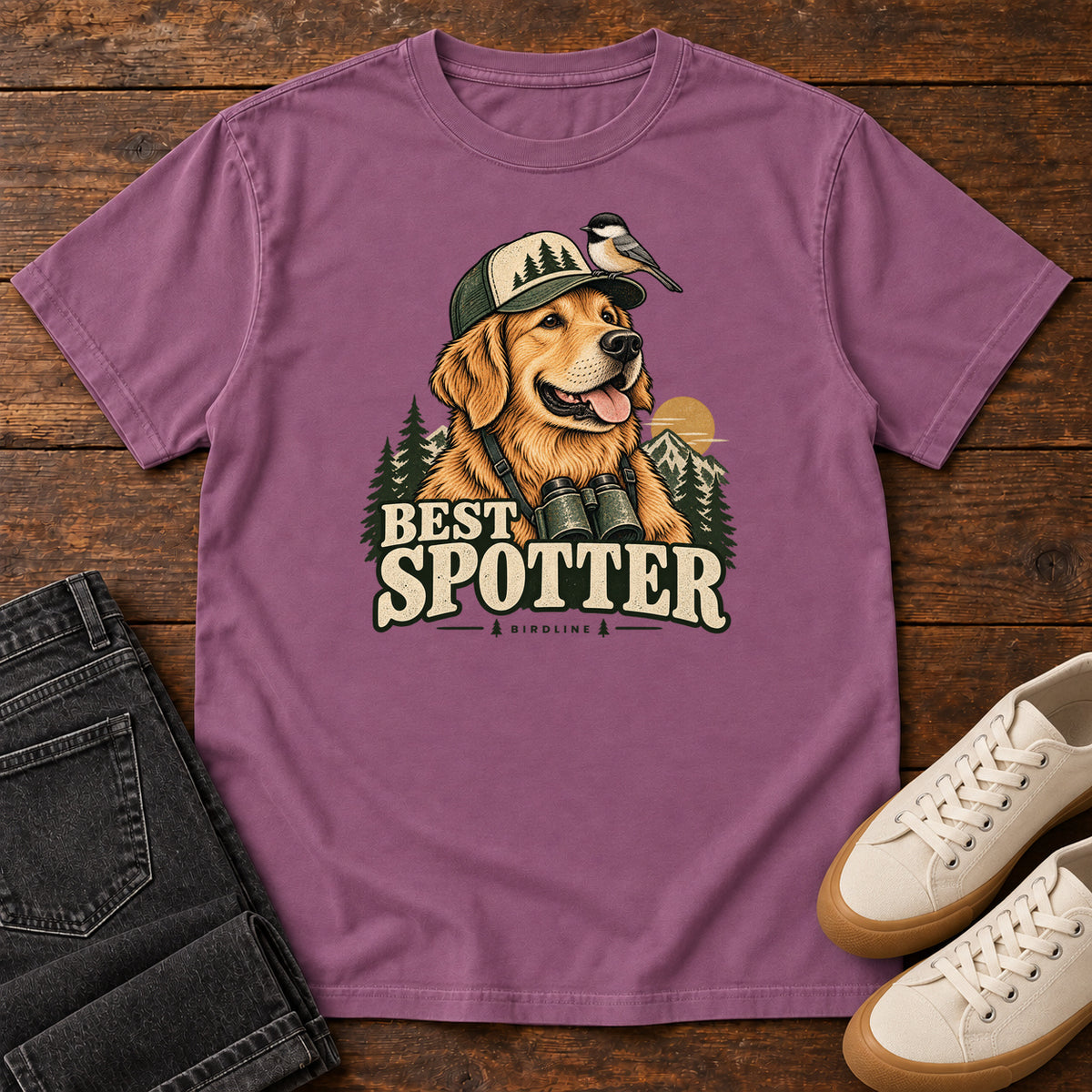 Berry Best Spotter T-Shirt with a golden dog wearing a cap and binoculars, with a small bird perched on the cap, front flat lay on wood.