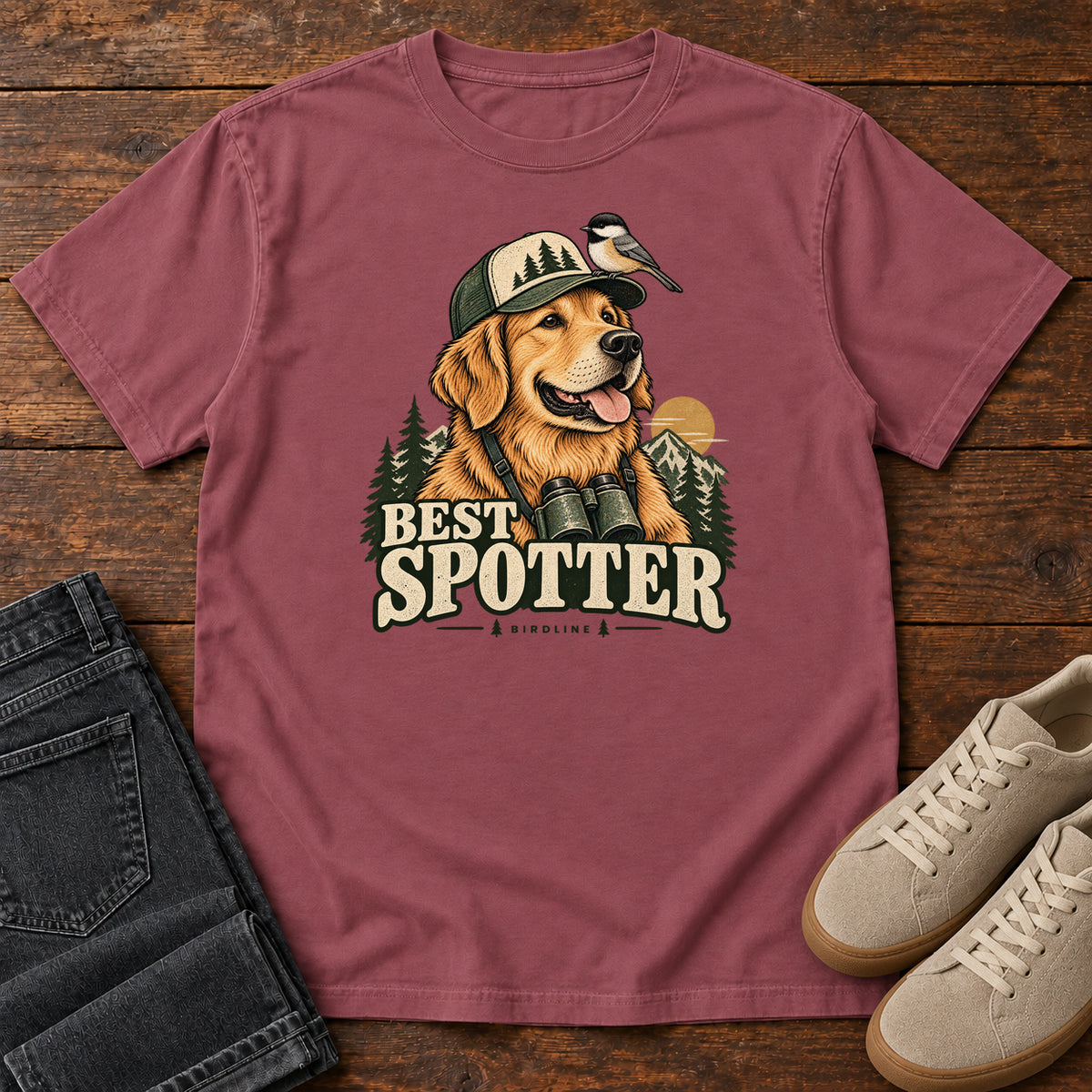Brick Best Spotter T-Shirt with a golden dog wearing a cap and binoculars, with a small bird perched on the cap, front flat lay on wood.