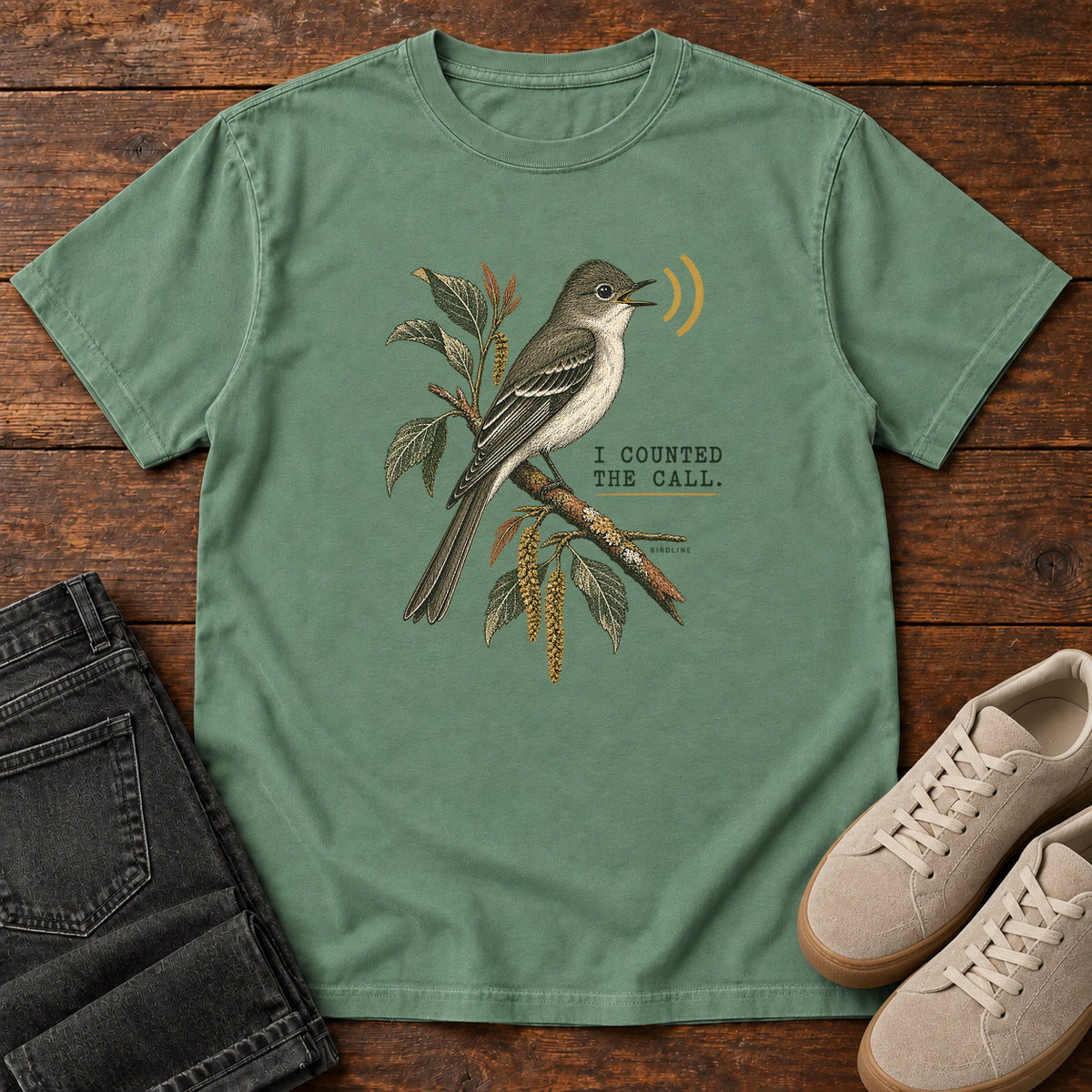Light Green I Counted the Call Songbird T-Shirt – Perched with a perched bird on a leafy branch and yellow sound-wave marks; front flat lay on wood.