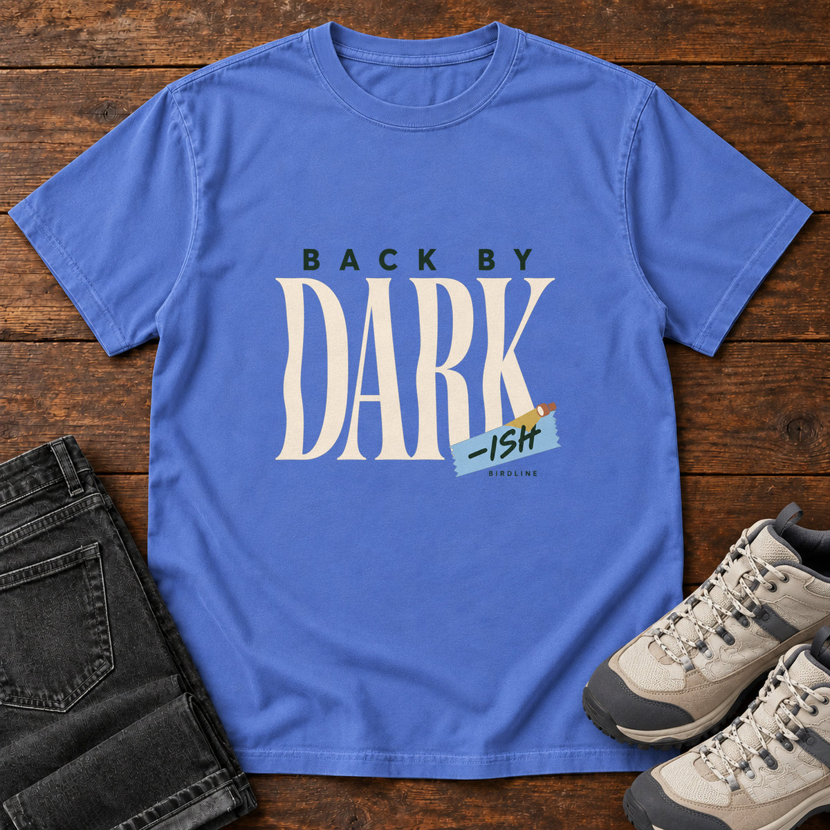 Mystic Blue Back by Dark-ish T-Shirt with tall cream Dark lettering and a small blue -ish label, front flat lay on wood.