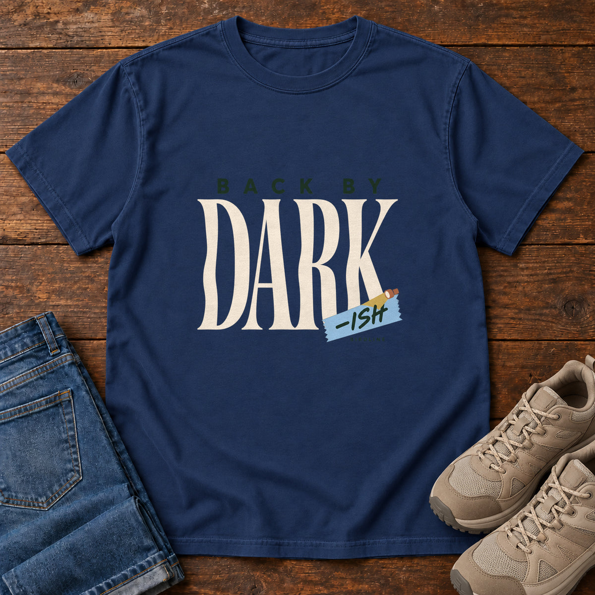 True Navy Back by Dark-ish T-Shirt with tall cream Dark lettering and a small blue -ish label, front flat lay on wood.