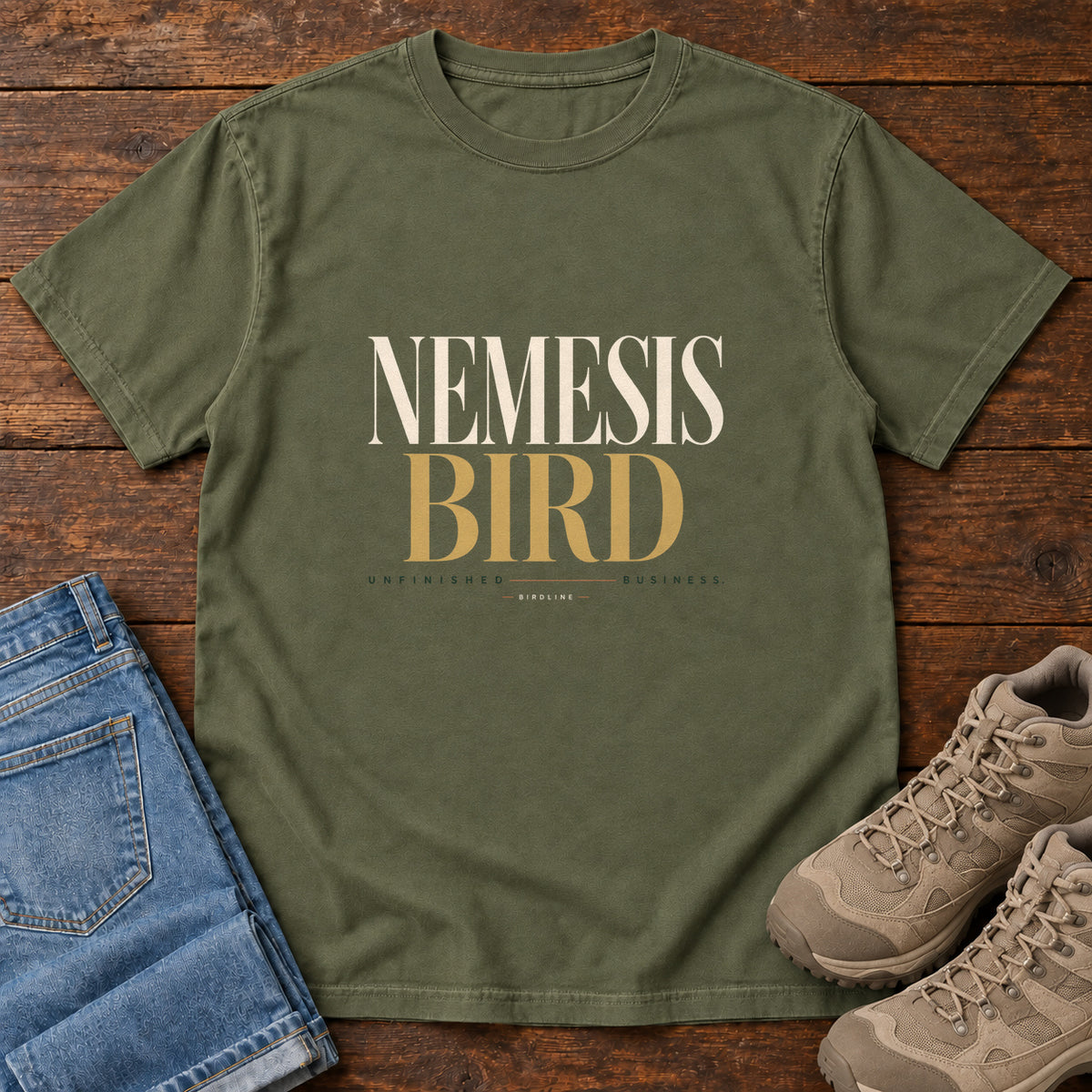 Hemp Nemesis Bird T-Shirt with cream-and-gold serif lettering, front flat lay on wood.