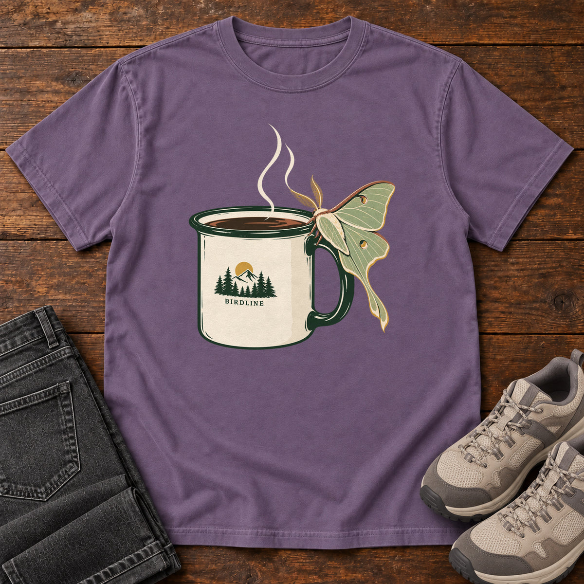 Grape Coffee and Luna Moth T-Shirt with a steaming cream camp mug with green trim and a pale green long-tailed moth; front flat lay on wood.