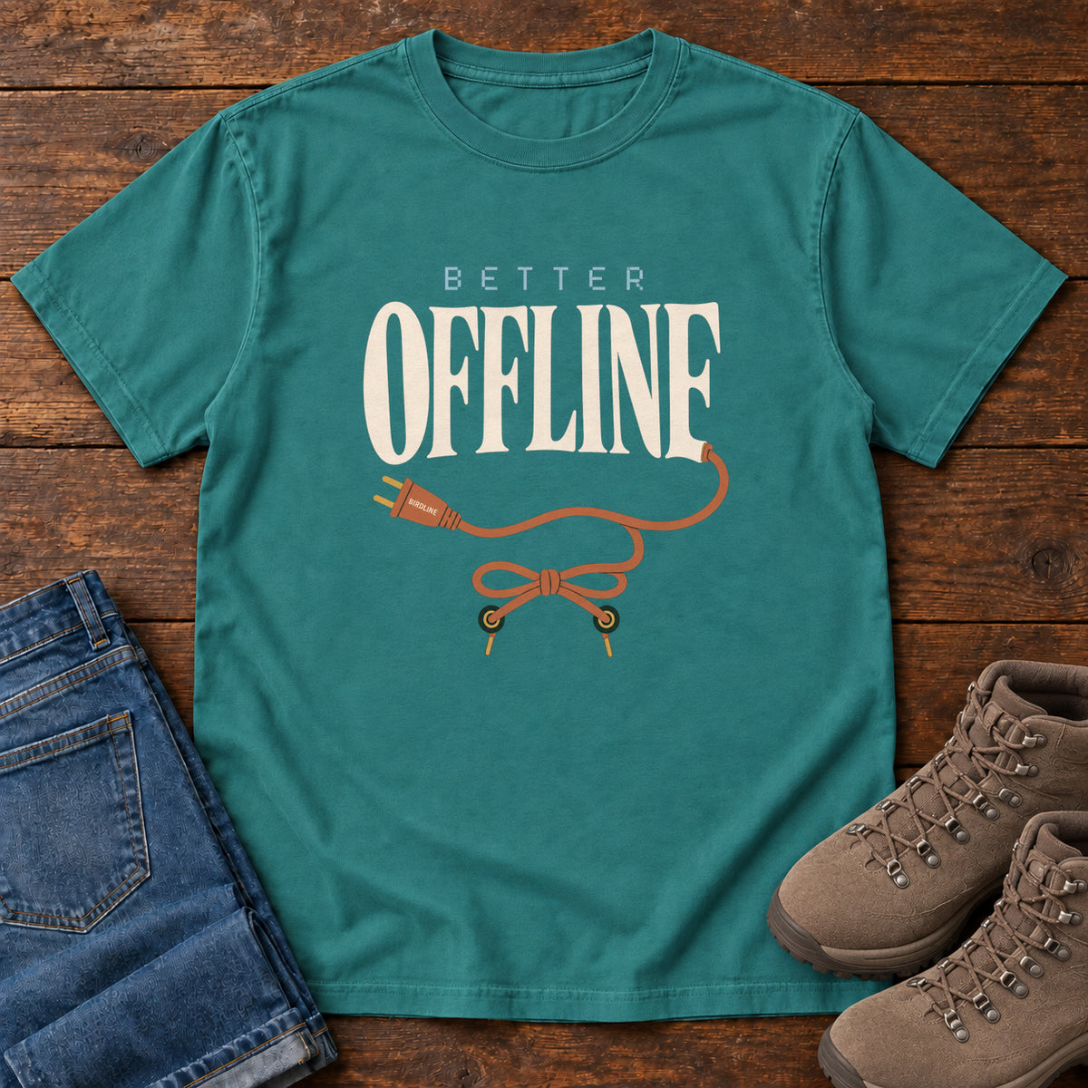 Emerald Better Offline T-Shirt with cream Better Offline lettering and an orange unplugged cord; front flat lay on wood.