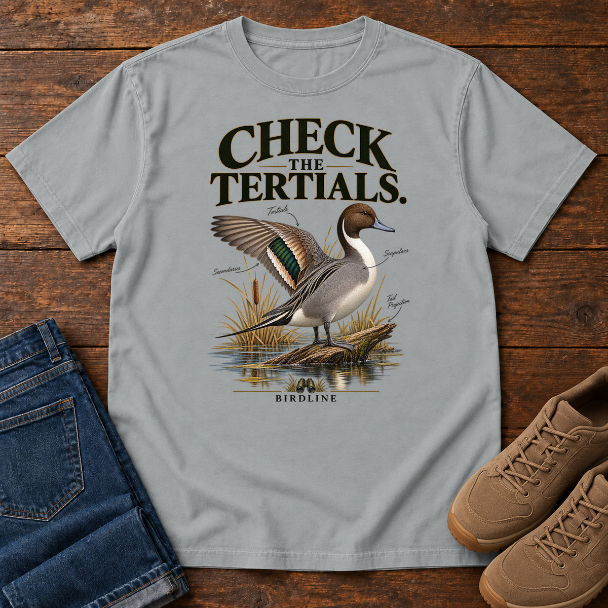 Granite Check the Tertials Duck T-Shirt with a duck raising one wing beside reeds and water; front flat lay on wood.