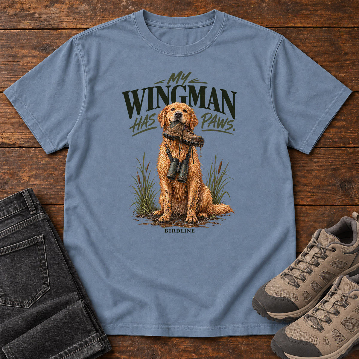 Blue Jean My Wingman Has Paws Retriever T-Shirt with a seated golden dog wearing binoculars beneath the slogan, front flat lay on wood.