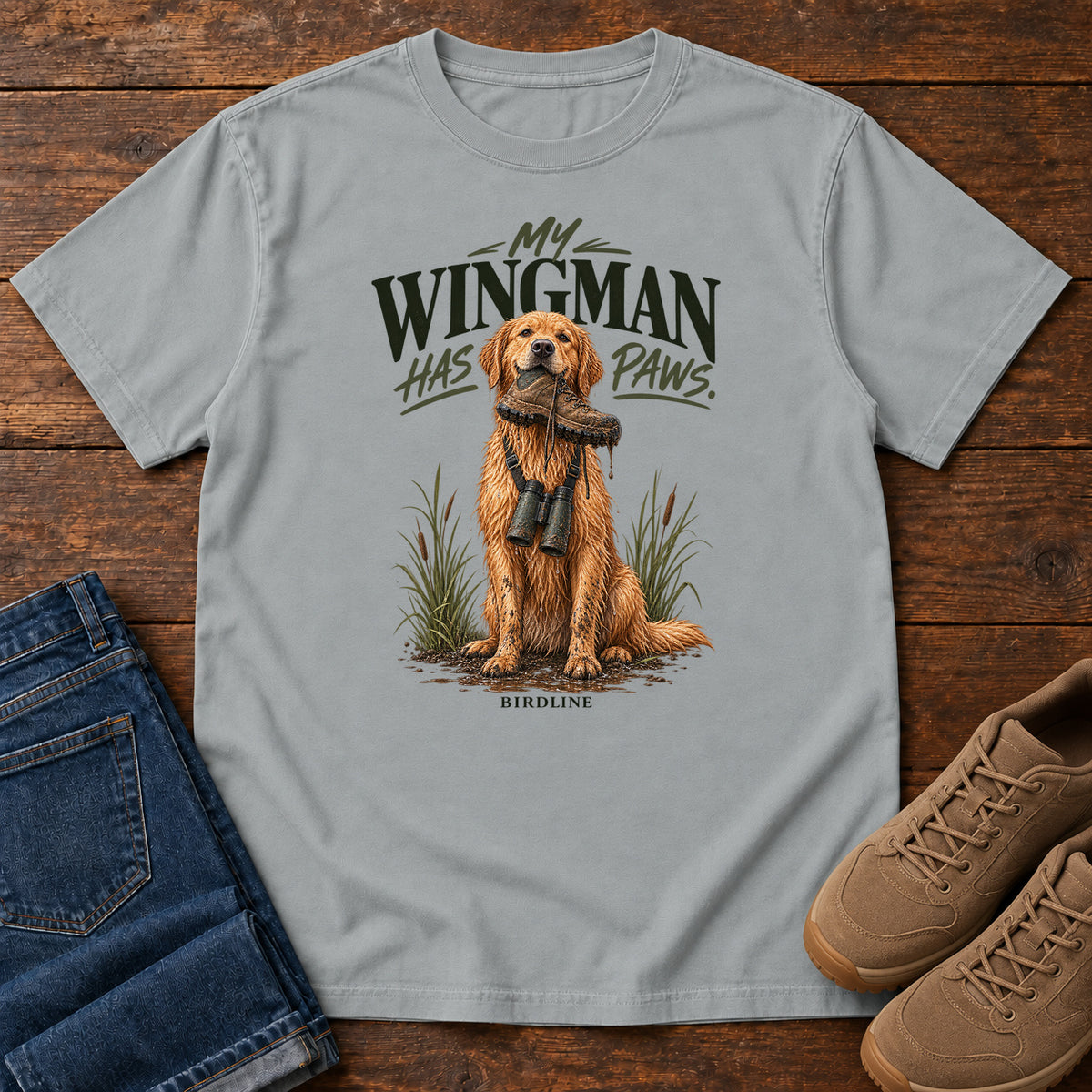 Granite My Wingman Has Paws Retriever T-Shirt with a seated golden dog wearing binoculars beneath the slogan, front flat lay on wood.