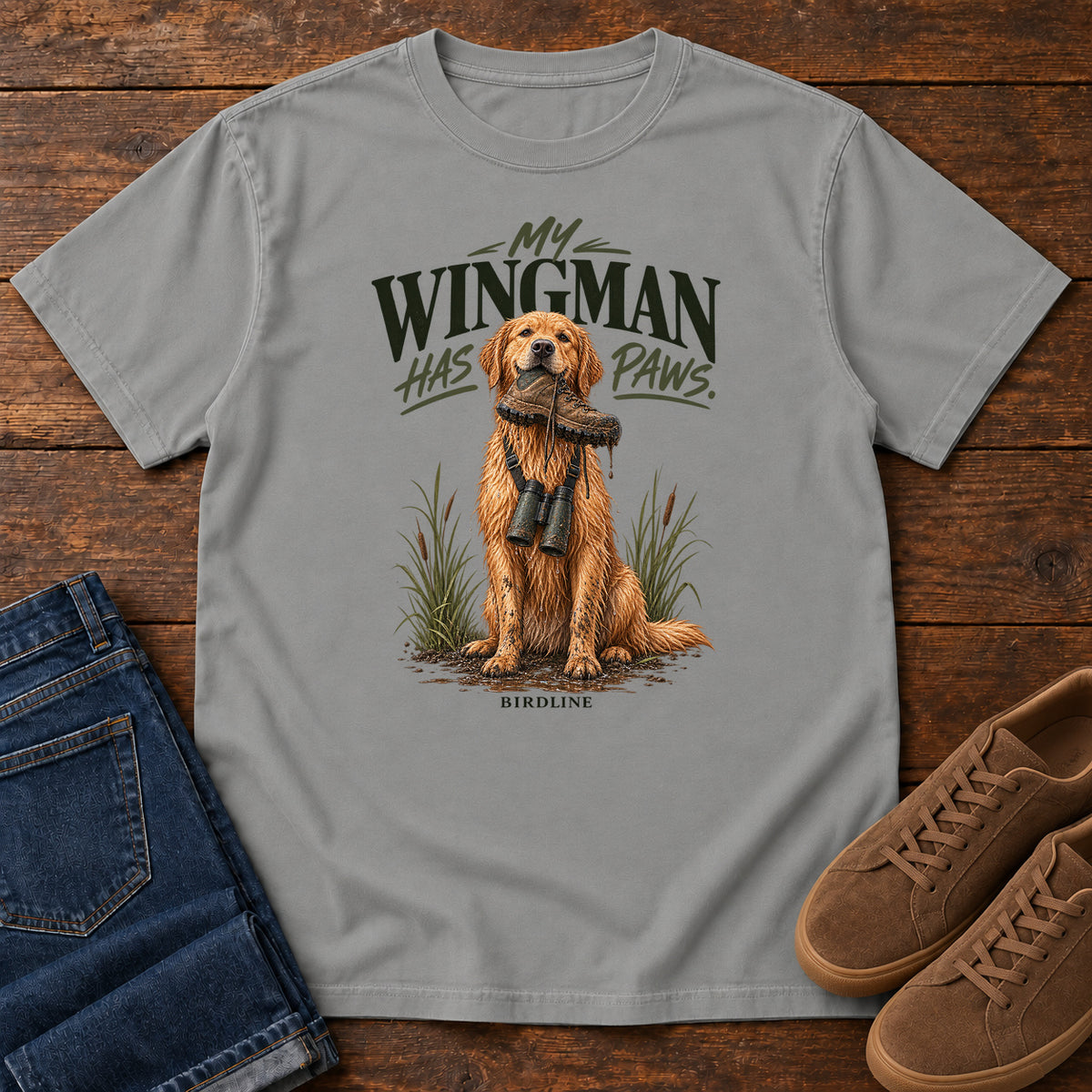 Grey My Wingman Has Paws Retriever T-Shirt with a seated golden dog wearing binoculars beneath the slogan, front flat lay on wood.