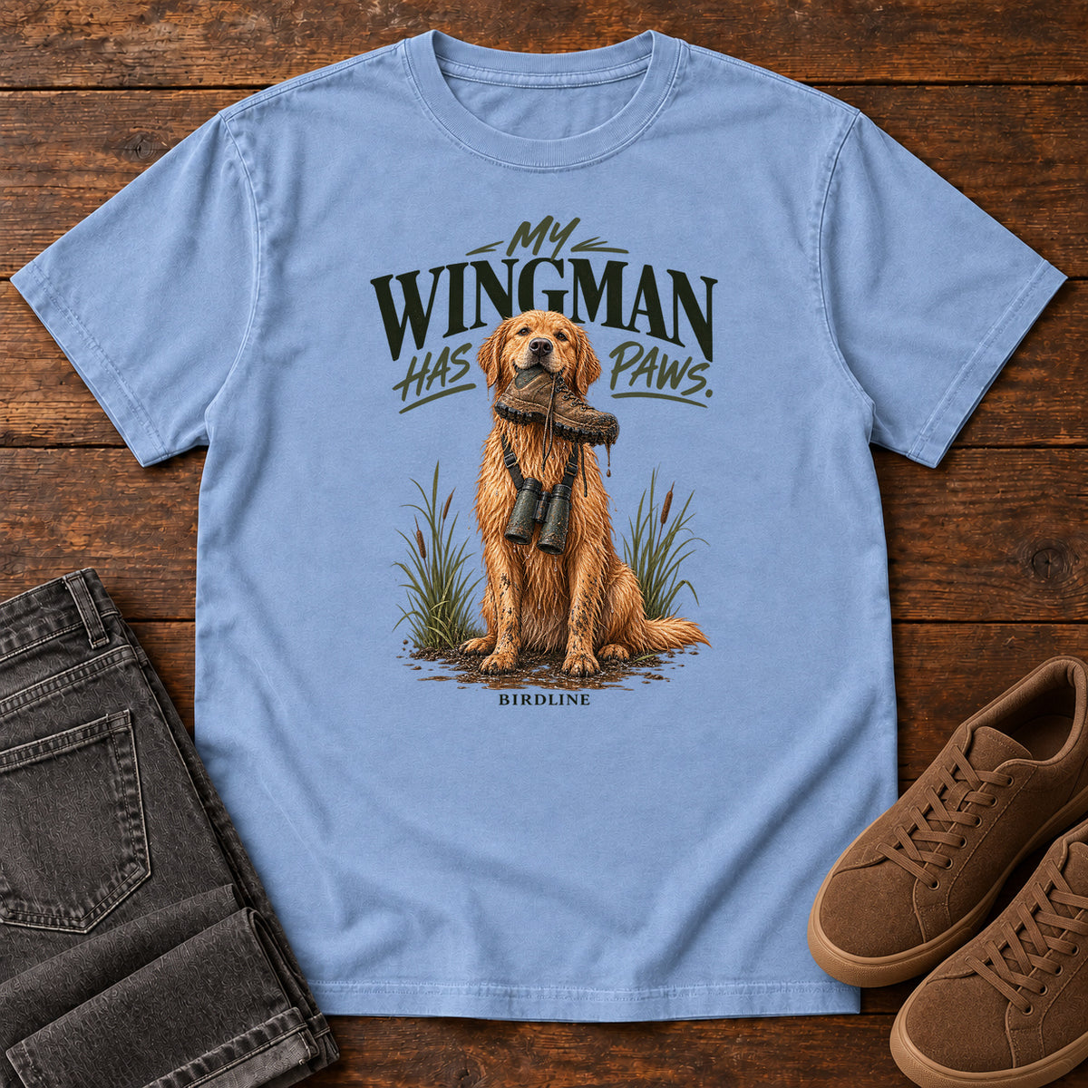 Washed Denim My Wingman Has Paws Retriever T-Shirt with a seated golden dog wearing binoculars beneath the slogan, front flat lay on wood.