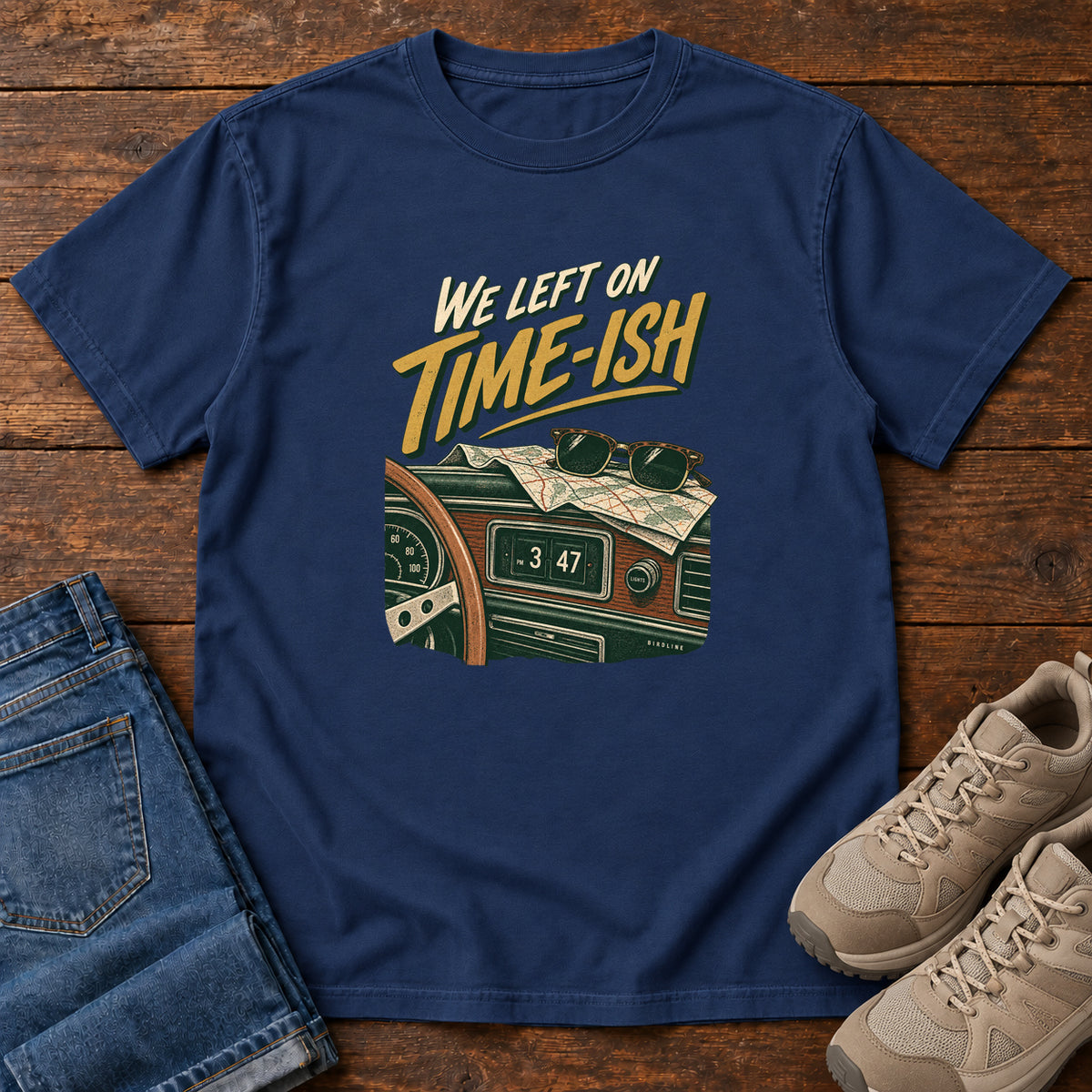 True Navy We Left on Time-Ish T-Shirt with a retro dashboard, folded map and sunglasses; front flat lay on wood.