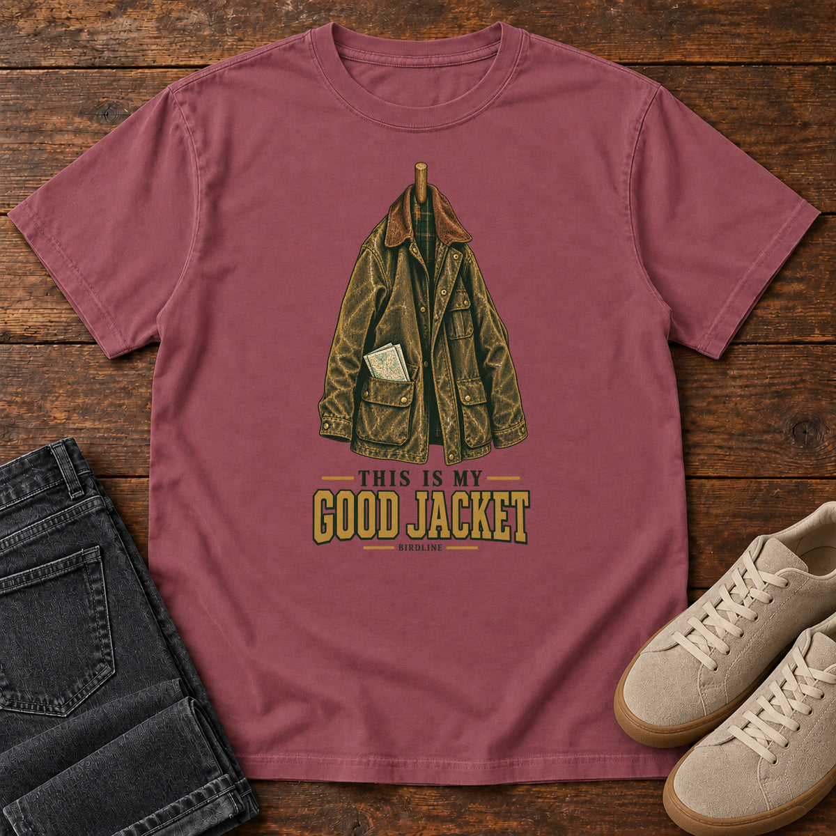 Brick This Is My Good Jacket T-Shirt with a hanging outdoor jacket and This Is My Good Jacket lettering; front flat lay on wood.