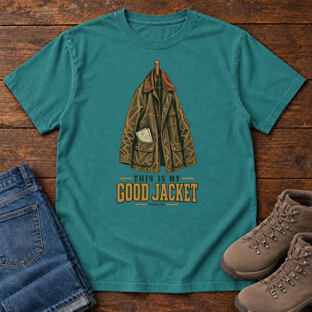 Emerald This Is My Good Jacket T-Shirt with a hanging outdoor jacket and This Is My Good Jacket lettering; front flat lay on wood.