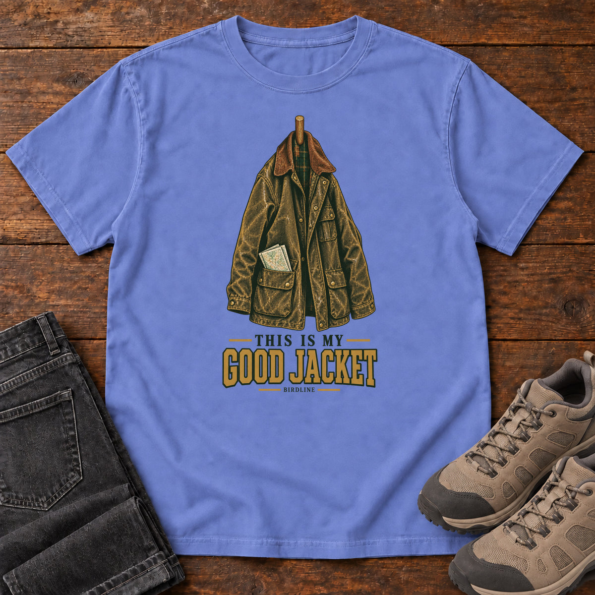 Flo Blue This Is My Good Jacket T-Shirt with a hanging outdoor jacket and This Is My Good Jacket lettering; front flat lay on wood.