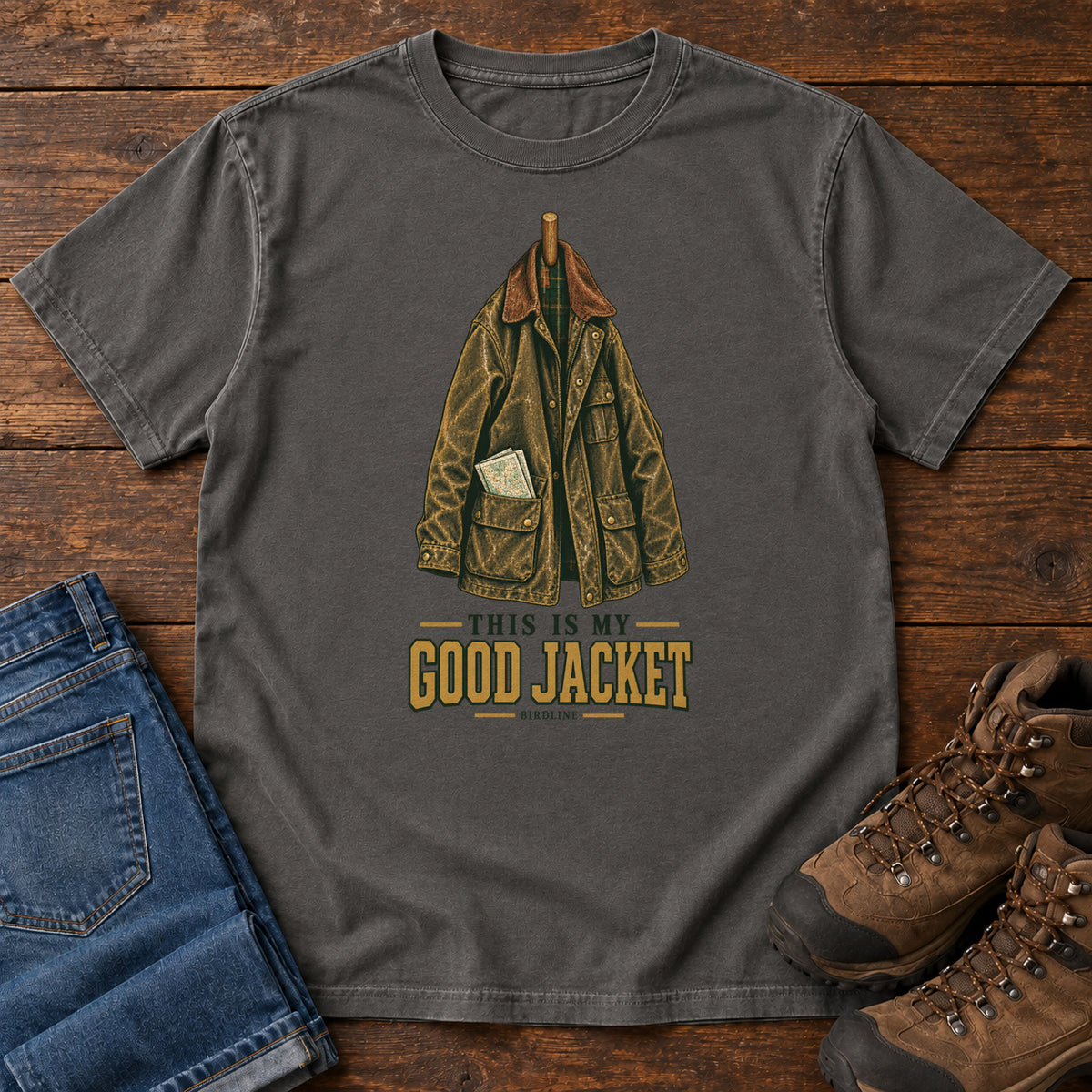 Pepper This Is My Good Jacket T-Shirt with a hanging outdoor jacket and This Is My Good Jacket lettering; front flat lay on wood.