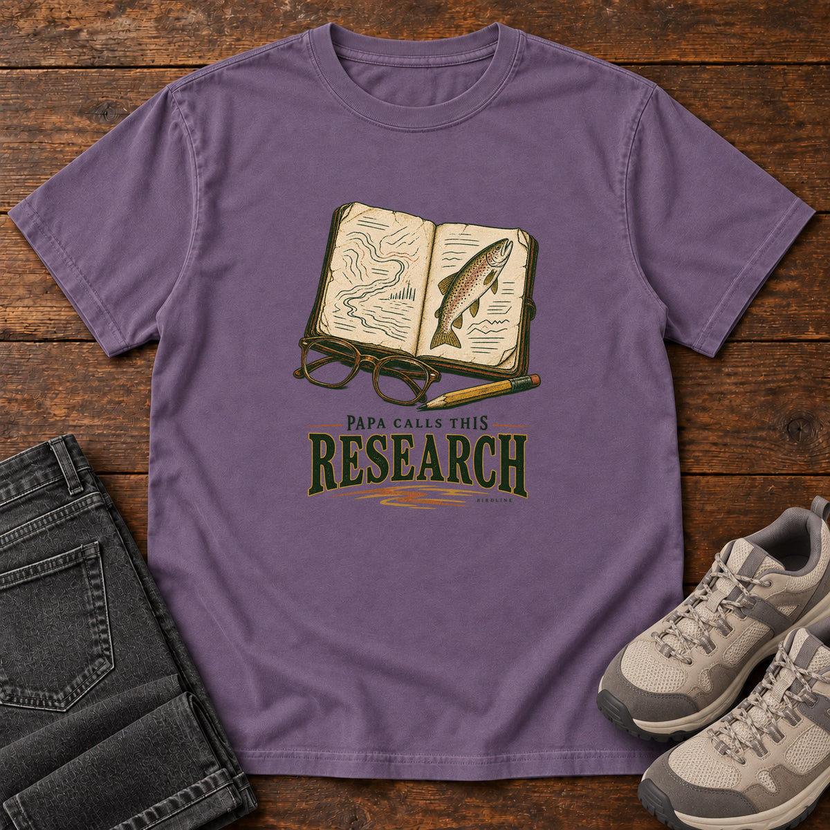 Grape Papa Calls This Research T-Shirt with an open field notebook showing a map and fish, with glasses and a pencil, front flat lay on wood.