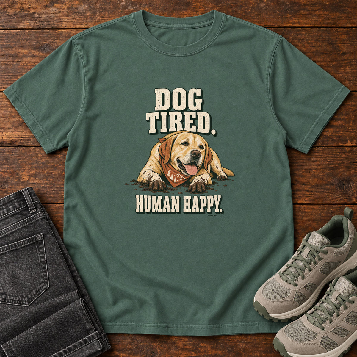 Dog Tired Human Happy T-Shirt in Blue Spruce, front laid flat on wood, featuring a resting golden-brown dog wearing an orange bandana between cream slogan lettering.
