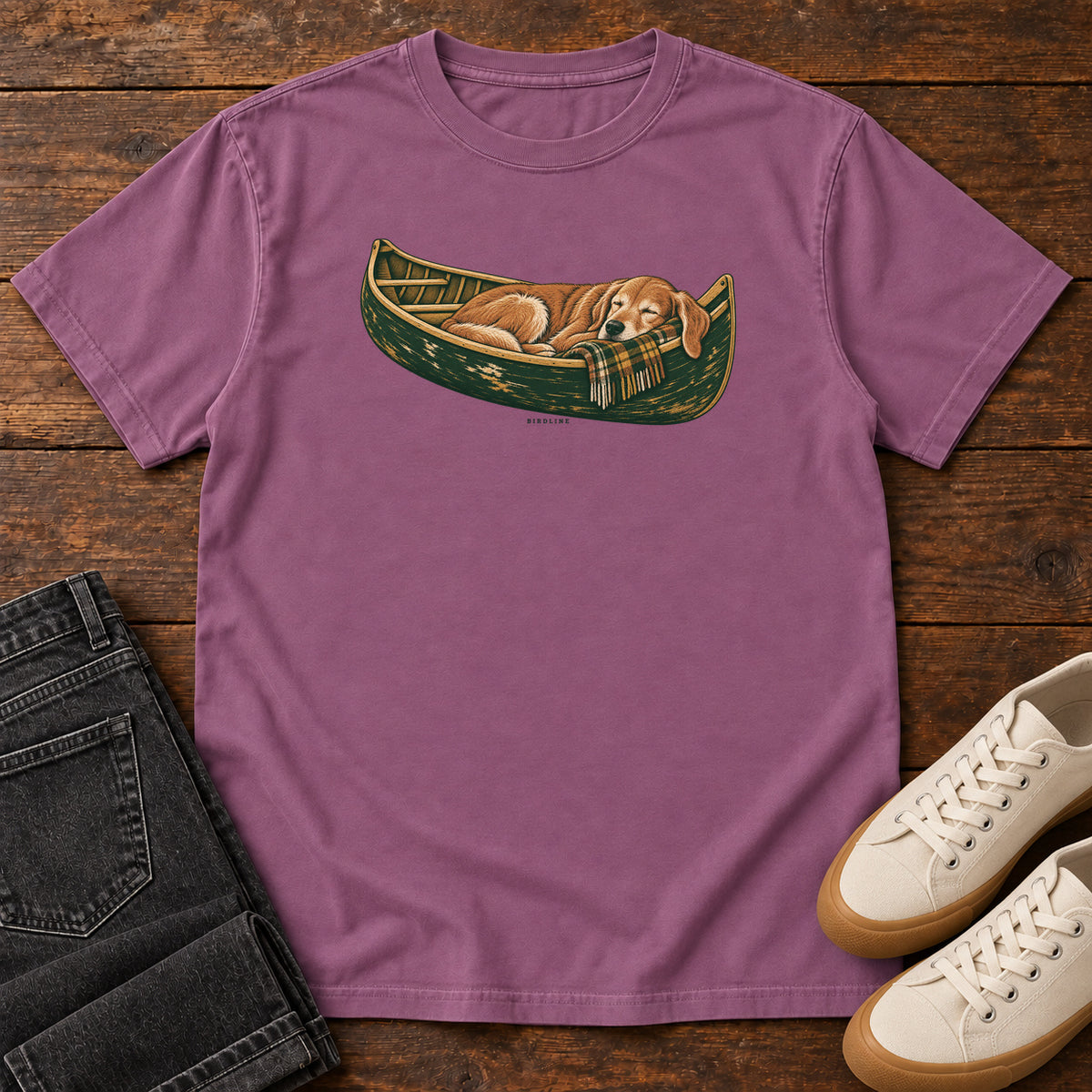 Berry Retriever Canoe Birdline T-Shirt with a golden dog resting in a green canoe, front flat lay on wood.