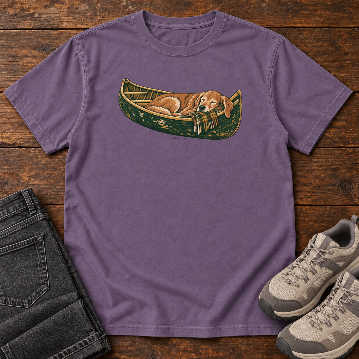 Grape Retriever Canoe Birdline T-Shirt with a golden dog resting in a green canoe, front flat lay on wood.