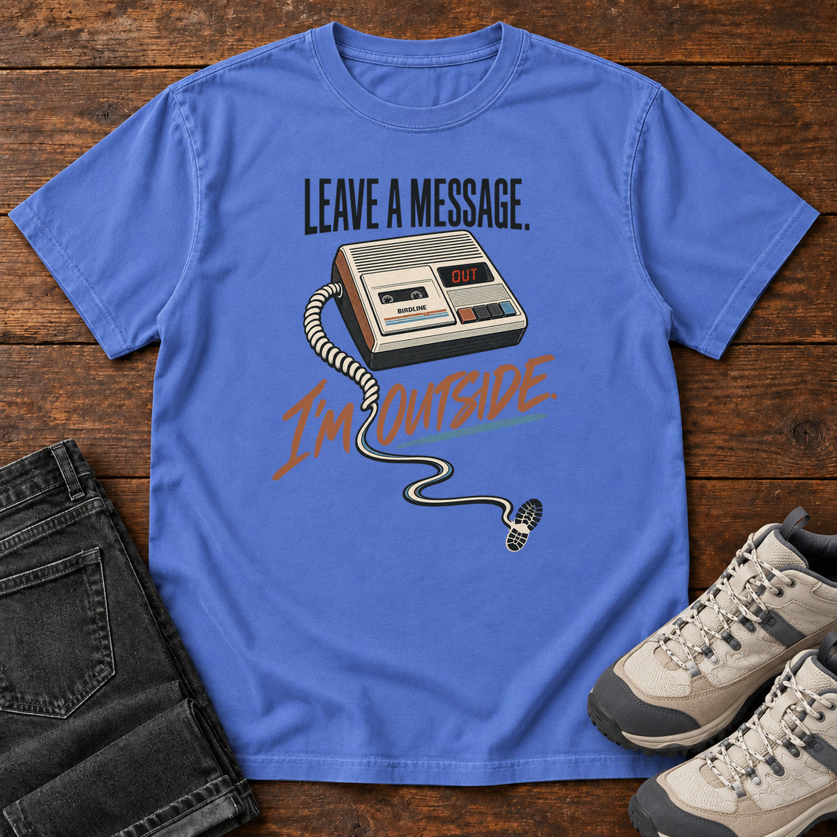 Mystic Blue Leave a Message I'm Outside T-Shirt with a retro answering machine, trailing cord and orange script, front flat lay on wood.