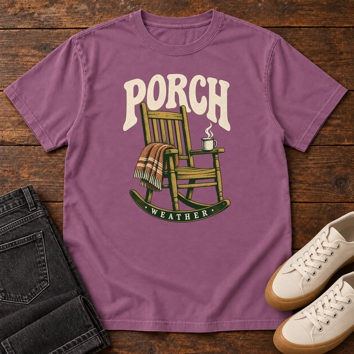 Berry Porch Weather T-Shirt with a wooden rocking chair with a striped blanket and steaming mug; front flat lay on wood.