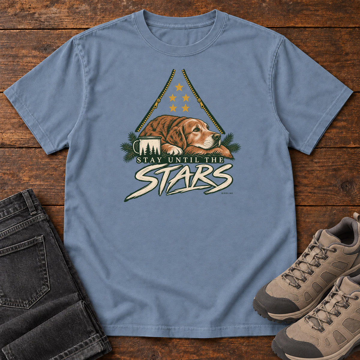 Blue Jean Stay Until the Stars T-Shirt with a resting brown dog beside a camp mug beneath gold stars and cream lettering, front flat lay on wood.