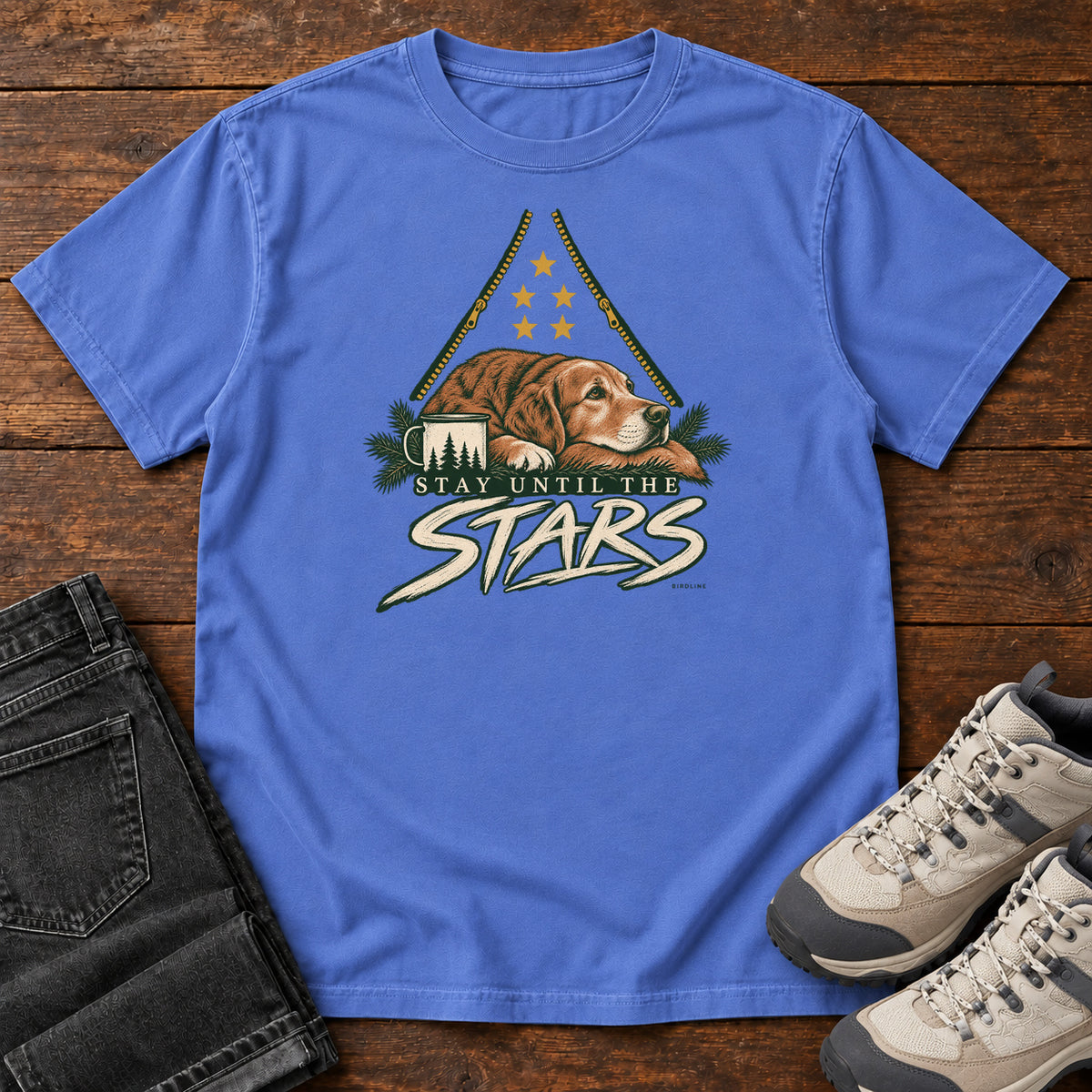 Mystic Blue Stay Until the Stars T-Shirt with a resting brown dog beside a camp mug beneath gold stars and cream lettering, front flat lay on wood.