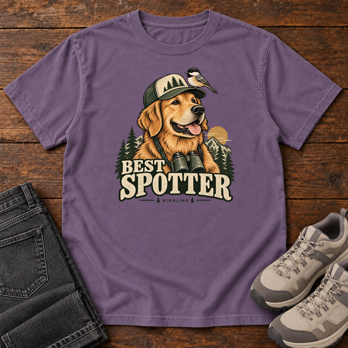 Grape Best Spotter T-Shirt with a golden dog wearing a cap and binoculars, with a small bird perched on the cap, front flat lay on wood.