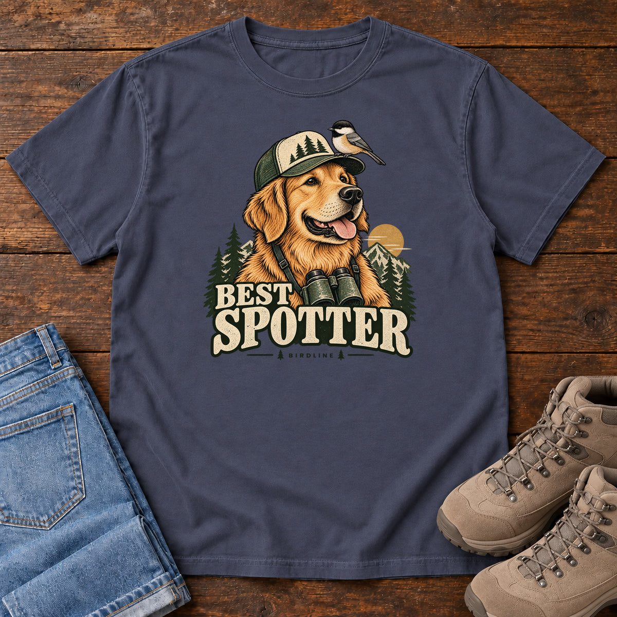 Navy Best Spotter T-Shirt with a golden dog wearing a cap and binoculars, with a small bird perched on the cap, front flat lay on wood.