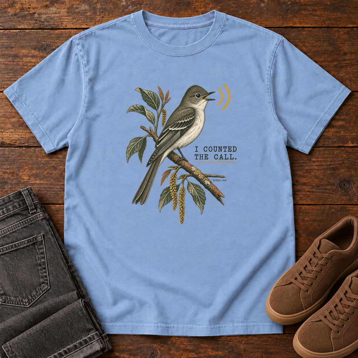 Washed Denim I Counted the Call Songbird T-Shirt – Perched with a perched bird on a leafy branch and yellow sound-wave marks; front flat lay on wood.