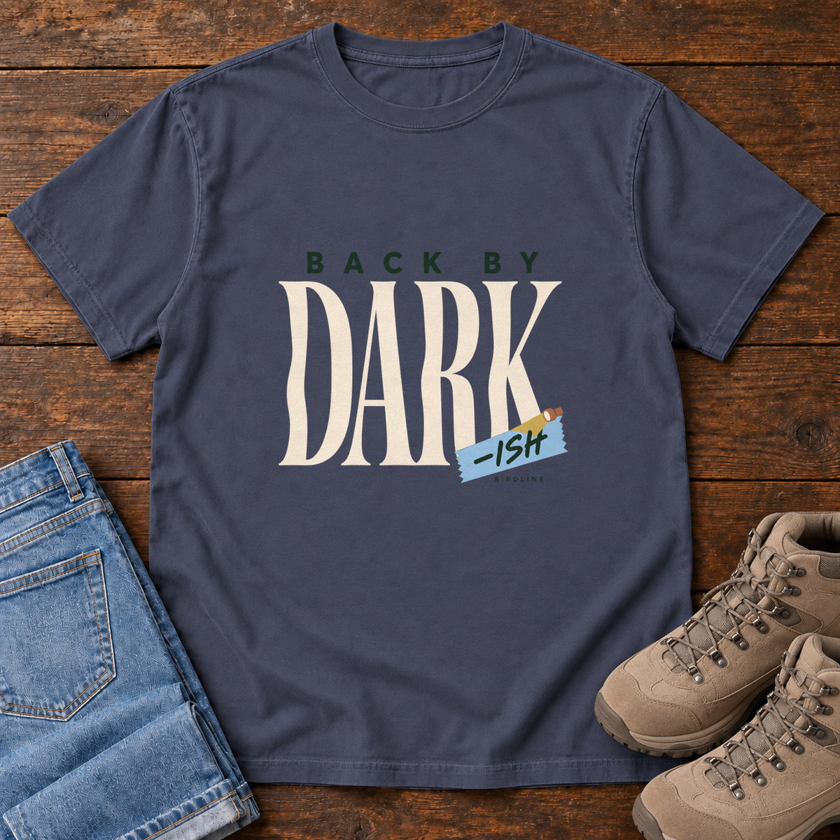Navy Back by Dark-ish T-Shirt with tall cream Dark lettering and a small blue -ish label, front flat lay on wood.