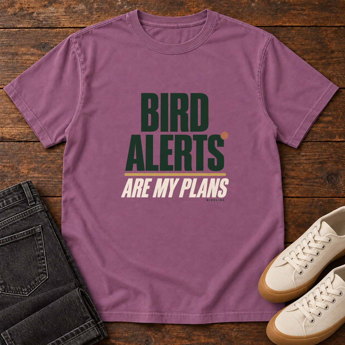 Berry Bird Alerts Are My Plans T-Shirt with stacked green-and-cream lettering and an orange accent; front flat lay on wood.