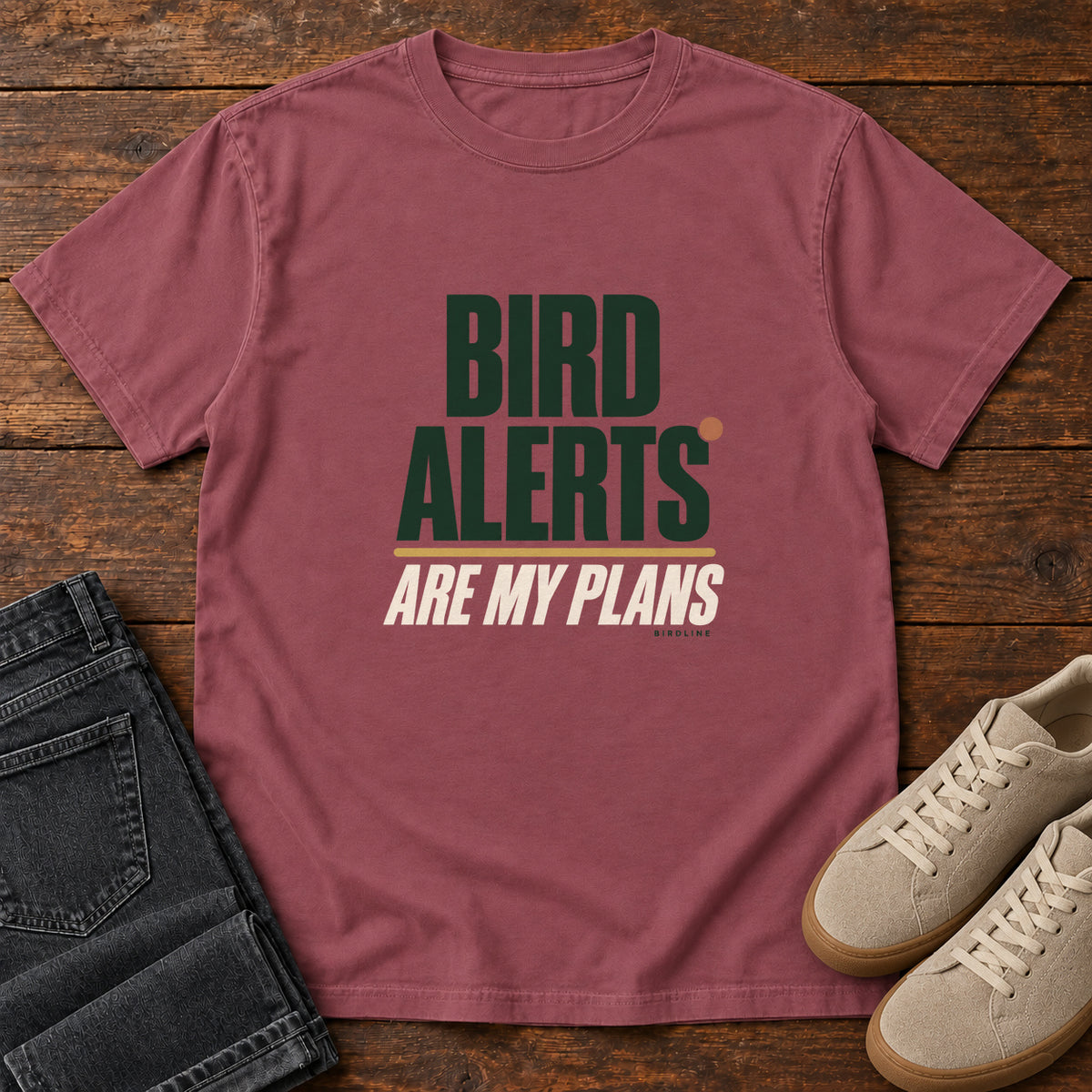 Brick Bird Alerts Are My Plans T-Shirt with stacked green-and-cream lettering and an orange accent; front flat lay on wood.