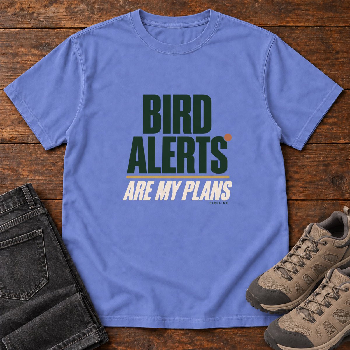 Flo Blue Bird Alerts Are My Plans T-Shirt with stacked green-and-cream lettering and an orange accent; front flat lay on wood.