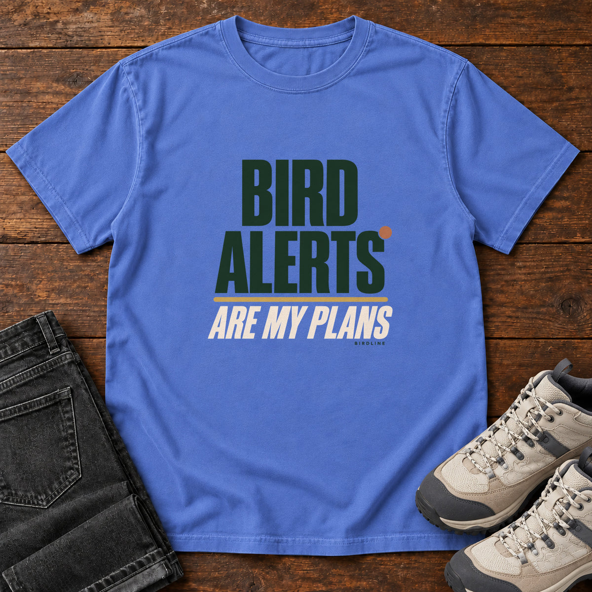 Mystic Blue Bird Alerts Are My Plans T-Shirt with stacked green-and-cream lettering and an orange accent; front flat lay on wood.